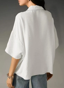 Detail of white short sleeve shirt showing textured crinkle fabric and drop shoulder design