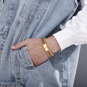Close-up of men's gold double-layer cuban chain bracelet worn with a denim jacket
