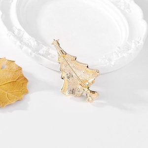 Christmas tree brooch with golden rhinestone and alloy details on white tray