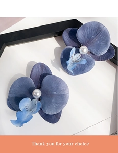 Macro view of blue butterfly orchid hair clip with silk fabric petals and central pearl