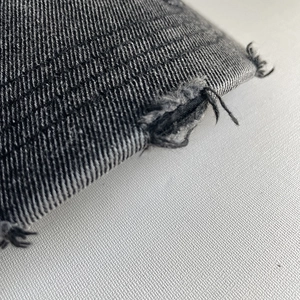 Close-up of distressed denim fabric with frayed edges and twill texture on a baseball cap