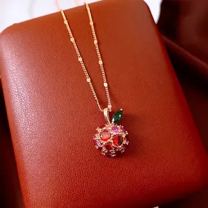 Gold plated apple pendant necklace with red and purple zircons on a leather pad