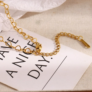 Macro shot of gold stainless steel heart link necklace on a white greeting card