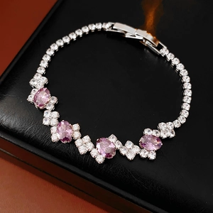 Close-up of geometric silver bracelet with purple zircon stones on a black leather display