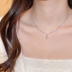 Close-up of silver necklace with elegant key, lock, and pearl charms on model neck