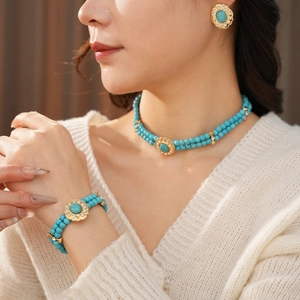 Gros plan d'un ensemble collier et bracelet en perles turquoise vintage avec fleurs dorées