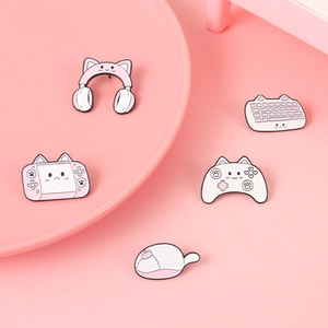 Macro shot of pink cat-themed gaming enamel pins featuring a keyboard and gamepad