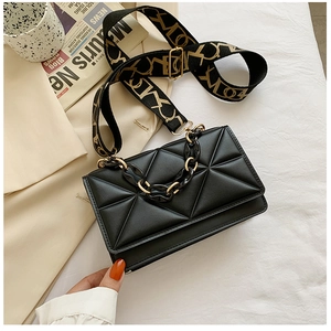 Detail of black quilted crossbody bag with metal chain and jacquard logo strap