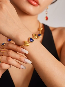 Primer plano de pulsera dorada con piedras azules en forma de corazón en la muñeca