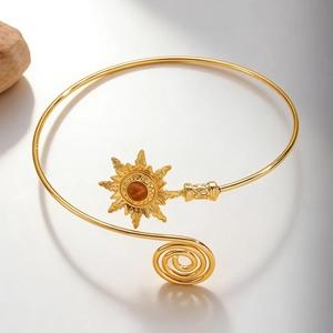 Detail of vintage gold sun arm cuff featuring a brown stone and spiral design