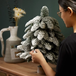 Miniature flocked PE Christmas tree with realistic snow on a rustic wooden base