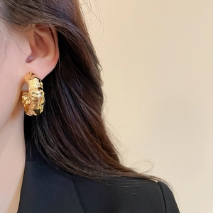 Close-up of gold textured liquid metal earrings on model for a modern retro look