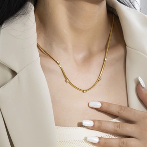 Close-up of gold snake chain necklace with five rectangular zircons on woman's neckline