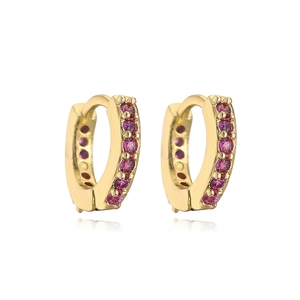 Detailed view of gold huggie earrings featuring micro-set pink gemstones on white surface
