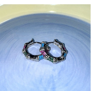 Détail de créoles bambou en argent avec pierres incrustées roses vertes et bleues