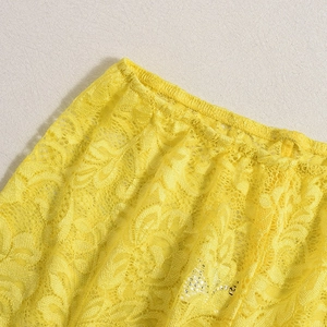 Détail du tissu en dentelle jaune aux motifs floraux délicats et ceinture élastique souple