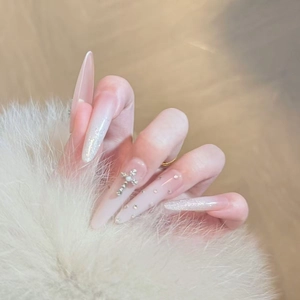 Long almond press-on nails with white gradient, silver crosses, and sparkling rhinestones