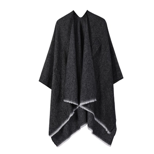 Detail of dark grey textured poncho with white fringe edges on a clean white background