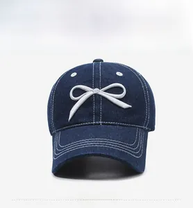 Detailed front view of washed denim baseball cap with white 3D bow embroidery
