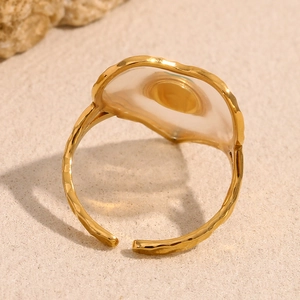 Top view of 18K gold plated ring with a translucent green heart acrylic stone on sand