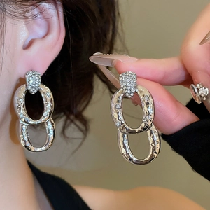 Detail of silver drop earrings with rhinestone studs and hammered metal double rings