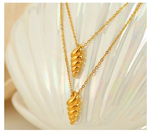 Macro shot of gold spiral seashell pendant necklaces on a pearl shell background