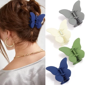 Détail de quatre pinces à cheveux papillon mates en bleu, vert, crème et gris