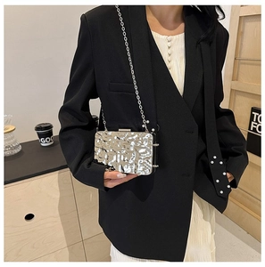 Silver evening clutch with hammered metallic texture and chain strap held by model