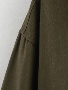 Detail of dark olive green cotton jacket showing heavy canvas texture and double stitching