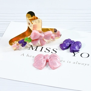 Détail de barrettes à cheveux nœud en résine rose et violette avec base en métal doré