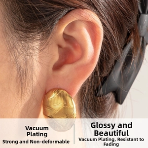 Detailed view of gold geometric stud earrings with cross-line texture on model
