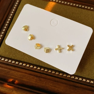 Macro shot of 6-piece golden minimalist earring set including heart and cross shapes