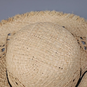 Macro shot of natural raffia straw weaving details with stylish frayed edge sun hat