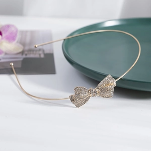 Elegant gold metal headband featuring a crystal rhinestone bow accessory on white background