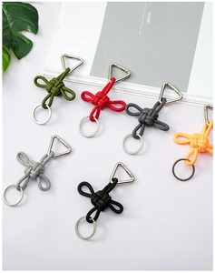 Macro display of colorful braided keychains with silver triangular hooks on white background