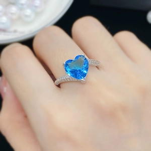 Detalle de anillo de plata con piedra de circón azul en forma de corazón en la mano