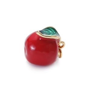 Detail view of a red enamel apple pendant with green leaves and gold metal plating