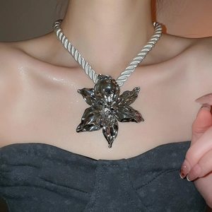 Detail of silver woven rope necklace with a 3D polished metal flower pendant on model