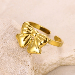 Detailed view of an adjustable golden bow ring on a textured stone surface display