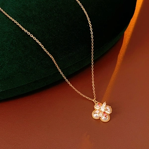 Detailansicht der goldenen Kleeblatt-Kette mit rosa Steinen und Perlen auf Leder