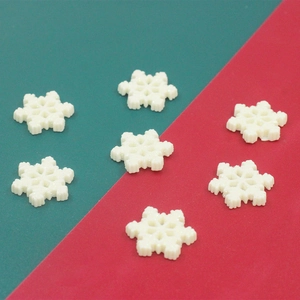 Close-up of seven white glittery resin snowflakes for DIY crafts on red and green background