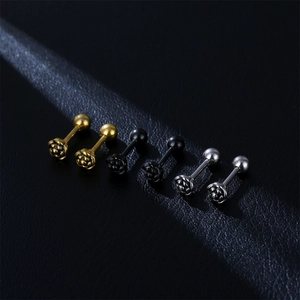 Detail of rose-shaped stainless steel ear studs in gold, black, and silver finishes