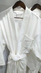 Detailed view of plush white cotton hotel bathrobe featuring a hood and waist belt tie