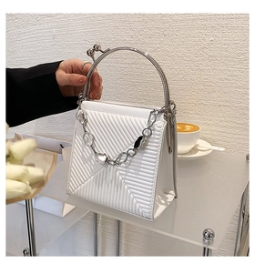 Detail of white quilted handbag with silver metal handle and ball clasp closure