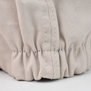Close-up of the beige knit beret featuring fine white stitching and elastic cuff texture