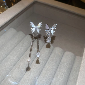 Detail of asymmetric butterfly earrings with butterfly wings and pearl tassel