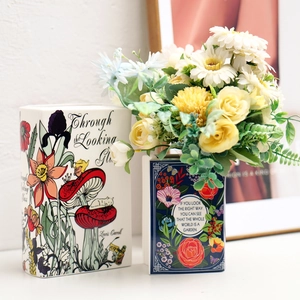 Creative book-shaped ceramic vases with literary motifs and vibrant artificial flowers