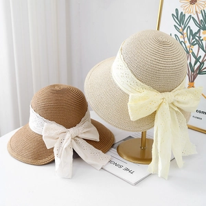 Women's straw sun hats with elegant lace bows in beige and tan on a minimalist stand