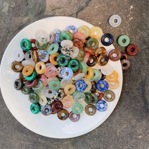 Mixed natural stone donut beads in aventurine and tiger eye on white porcelain tray