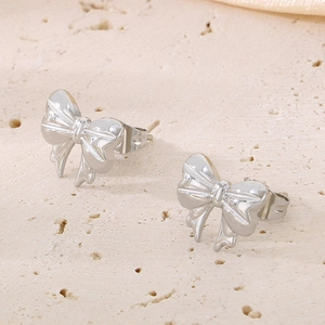 Vue macro de boucles d'oreilles nœud argenté sur fond de pierre naturelle et de soie douce